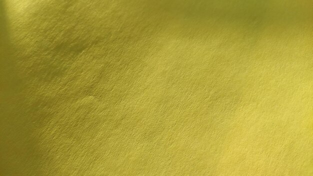 The paper or fabric material is bright yellow Closeup Slightly folded sheet Light gradient and accentuated rough surface texture Background or product sample Sunny cheerful yellow