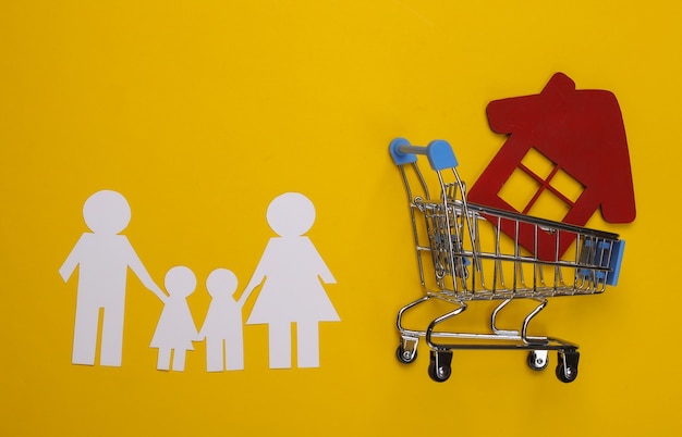 Paper family together and shopping trolley with house on a yellow. House buying concept