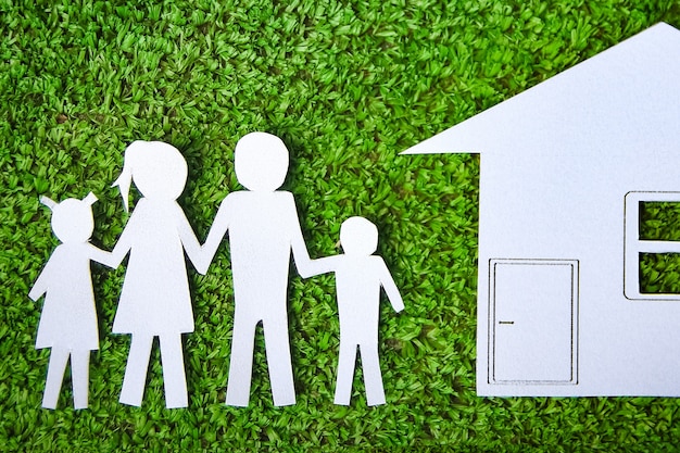 Paper family with a house on a background of grass