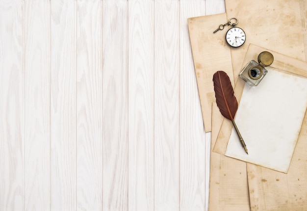 Paper, feather pen and inkwell. Vintage office supplies on wooden table