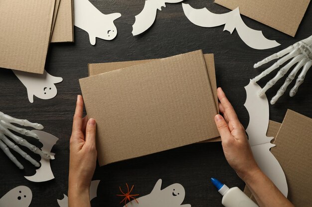 Photo paper ghosts and bats cardboard and female hands on wooden background top view