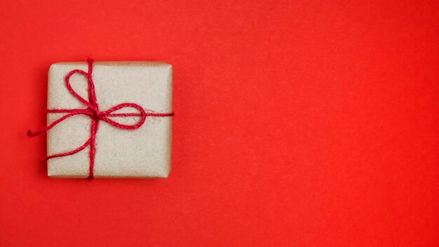 Бумажная подарочная коробка на красном фоне. Вид сверху, место для текста