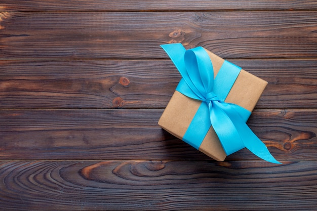 Paper gift box with blue ribbon on dark wood background. top view with copy space