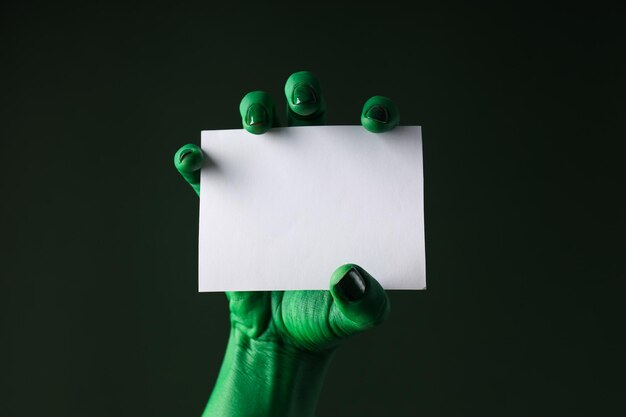 Paper in green female hand on green background close up