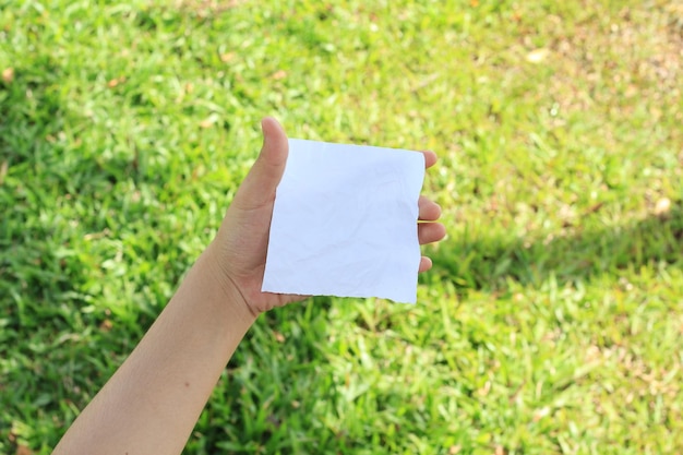 paper in hand on grass background