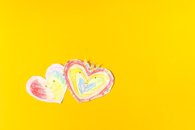 Paper hearts on bright yellow paper background. Child's creation for Valentine's day.