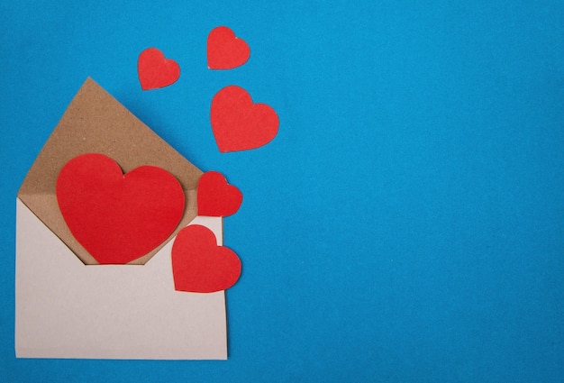 Paper hearts of different sizes in an envelope on blue