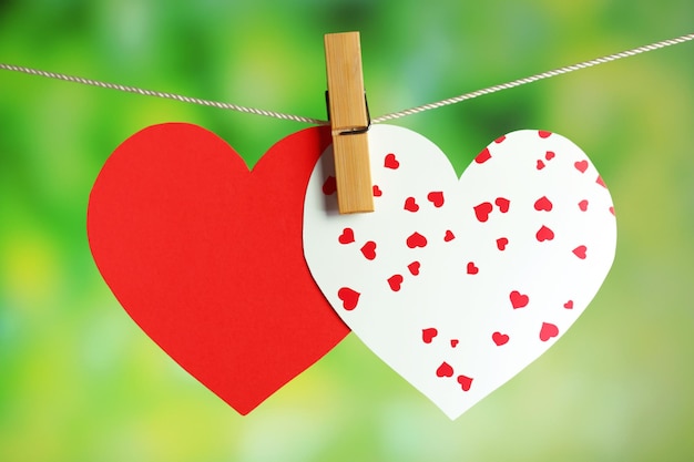 Paper hearts hanging on rope on bright background