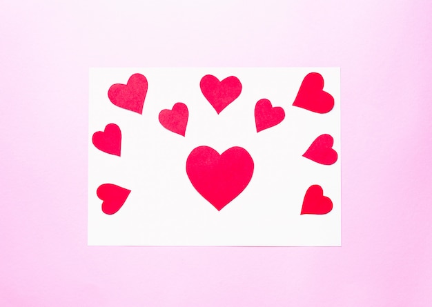 Photo paper hearts over pink surface valentine's day concept, top view.
