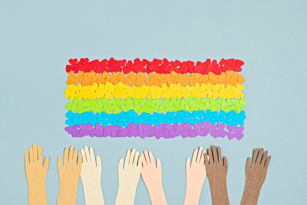 LGBTゲイプライドの虹色のストライプのシンボルと旗の形をした紙のハート。愛、多様性、寛容、平等の概念