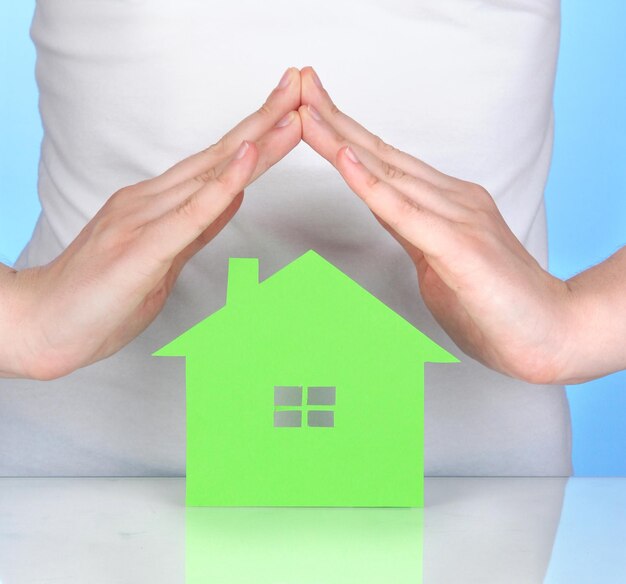Photo paper house in hands on blue background