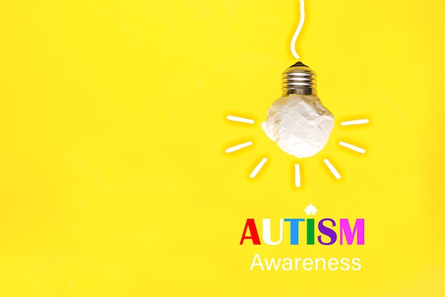 Paper light bulb on a yellow background, world Autism awareness day
