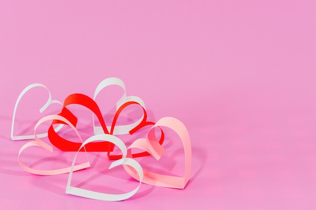 Бумажные сердца любви на розовом фоне