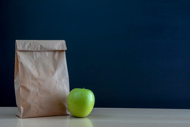 Paper lunch bag on desk with apple