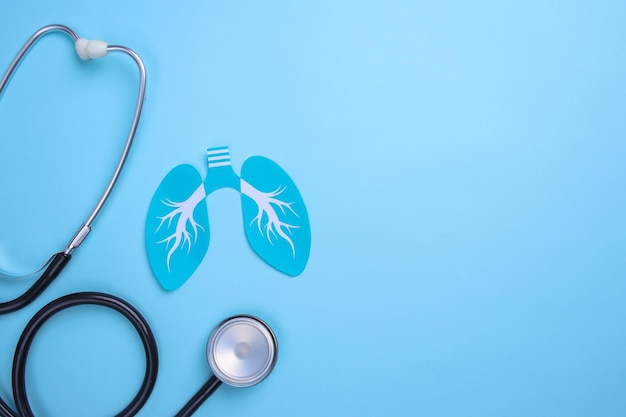 Paper lungs and medical stethoscope on blue background World tuberculosis day pneumonia and respir