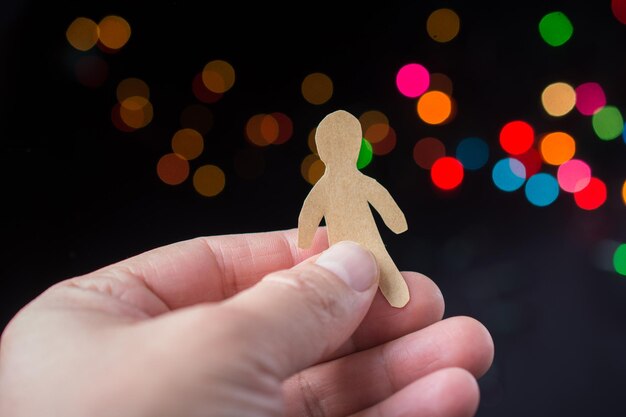 Foto forma di uomo di carta in mano su sfondo chiaro bokeh