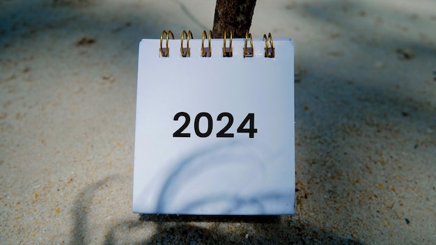 Paper mockup with 2024 and happy new year writing over beach sand background banner with copy space