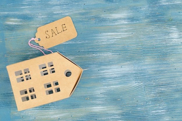 Paper model of residential building with sale tag