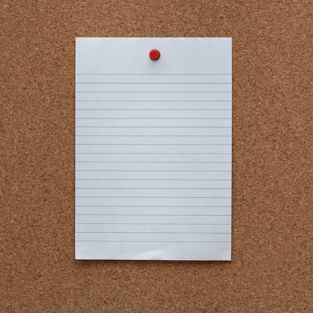 Paper note with pushpin on cork board background.