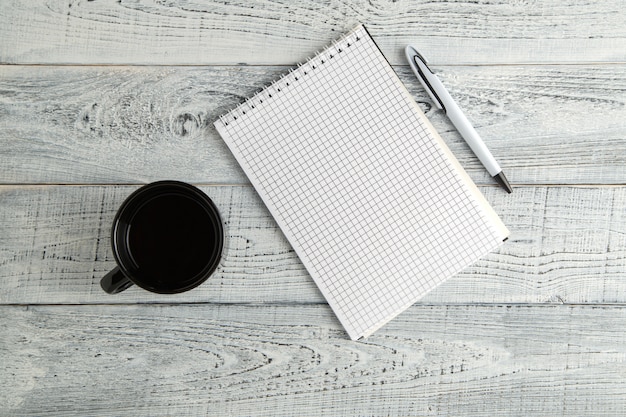 Paper notebook, pen and Cup of tea or coffee on vintage shabby white wood, top view