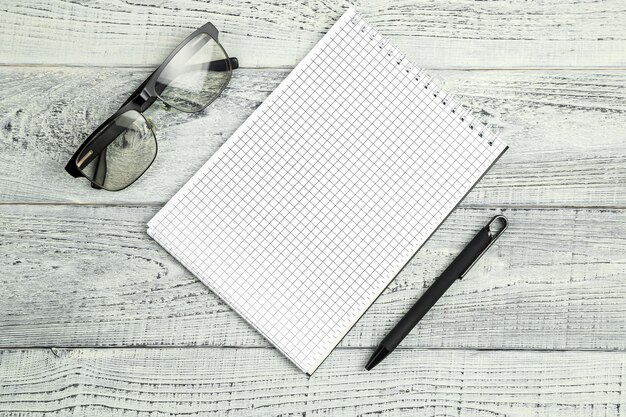 Photo paper notebook with ballpoint pen and optical glasses on wooden isolated background