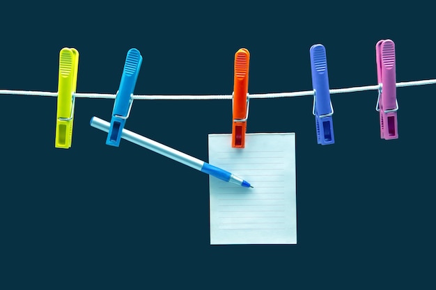 Foto blocco note di carta per promemoria e penna appesa a mollette colorate
