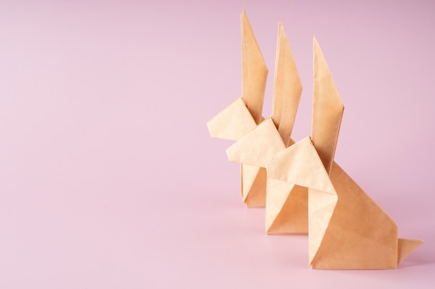 Paper origami bunny on pink background. Crafts made of paper. The minimal concept of Easter or the year of the rabbit. Easter bunny, copy space.