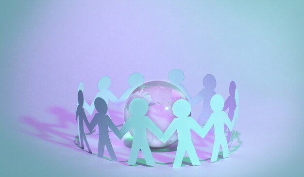 Photo paper people standing in a circle around glass globe