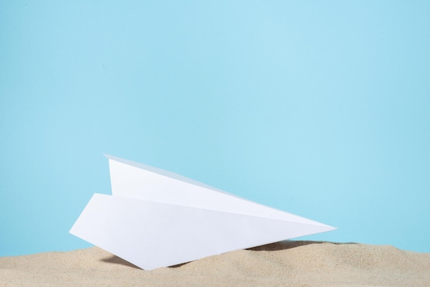 Paper plane on the sand on a blue background template