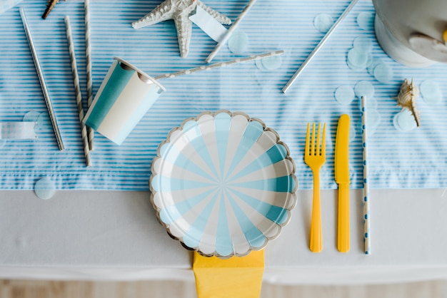 Paper plates on prepared birthday table with for children or girls party in sky blue and white colors. Baby boy shower. Close up, top view