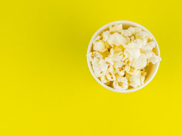 Paper popcorn Cup on a yellow surface. Place for your text.