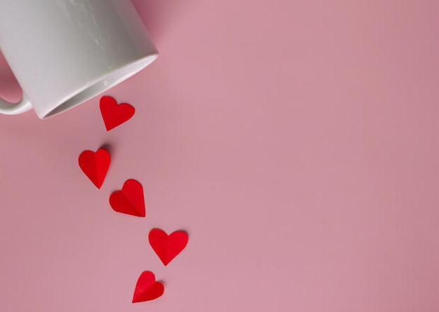 Foto il cuore rosso di carta viene versato dalla tazza di caffè bianco per presentare l'amore il giorno di san valentino
