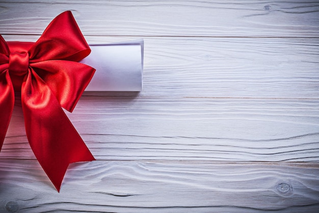 Paper scroll with red bow on wooden board holidays concept