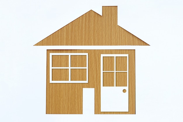 Paper shaped house on a background of brown wood.