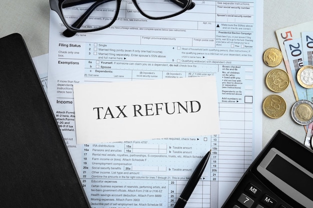 Paper sheet with text TAX REFUND and documents on table