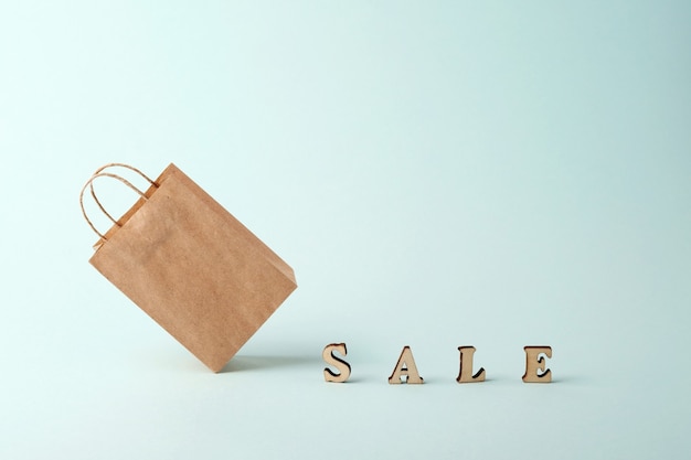 A paper shopping bag and the word sale on a blue background. The concept of delivery of purchases and sales.