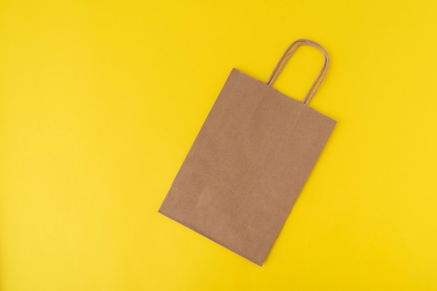 Paper shopping bag on yellow background. Copy space. Mock up. Zero waste.
