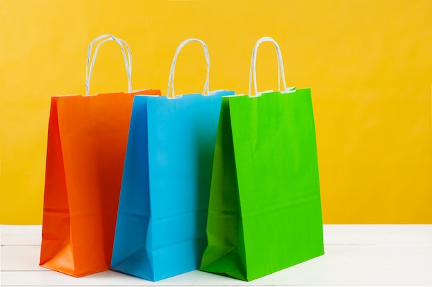 Paper shopping bags on bright yellow background