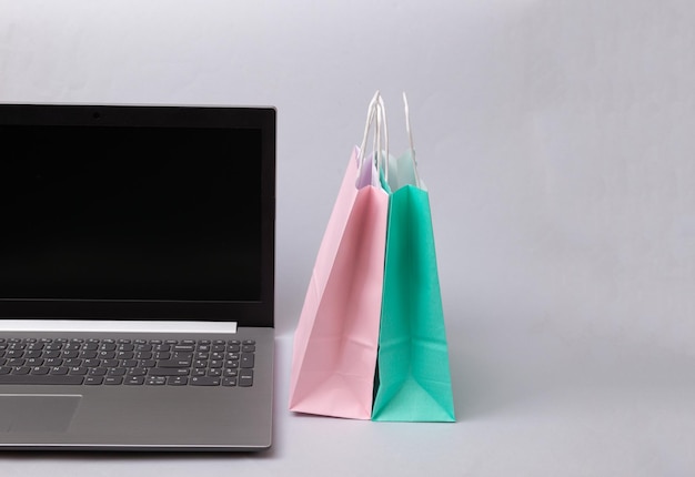 Paper shopping bags and laptop on white background online\
shopping concept
