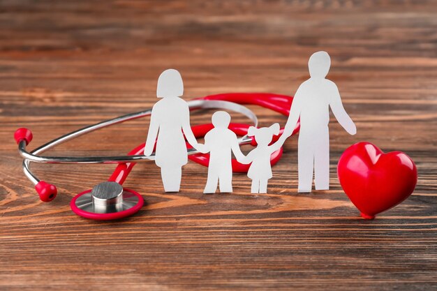 Бумажный силуэт семейного стетоскопа и сердца на деревянном фоне Концепция медицинского страхования