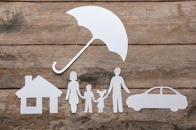 Paper silhouette of family, umbrella, house and car on wooden surface. Life insurance concept