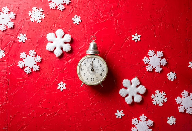 paper snowflakes and clock on red background