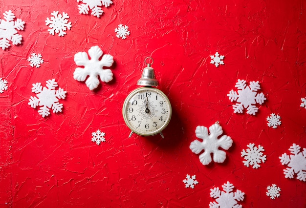 Paper snowflakes and clock on red background