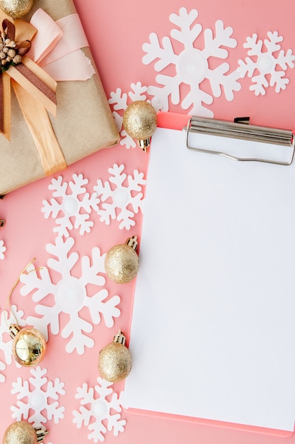 Paper snowflakes, folder and golden balls on pink background