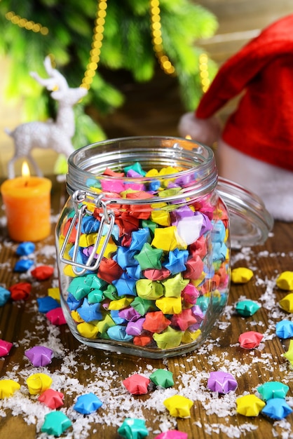 Paper stars with dreams in jar on table on wooden background