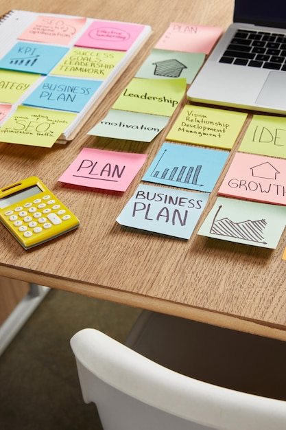 Paper stickers with business strategy, calculator and laptop on table