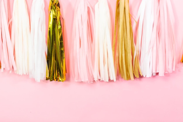 Photo paper tassel garland on a pink wall at the kids birthday party.