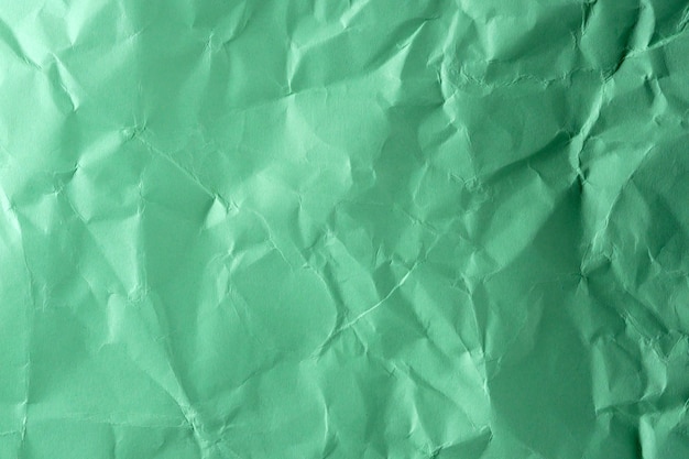 Бумажный текстурированный фон из мятой зеленой бумаги крупным планом макросъемка с высокой детализацией