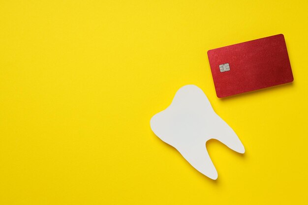 Paper tooth and bank card on yellow background space for text