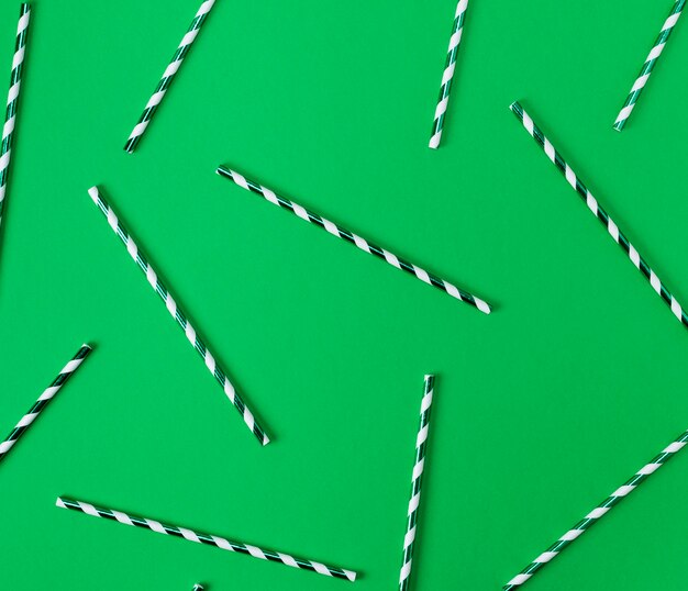Бумажные тубы для коктейлей разбросаны на зеленом фоне